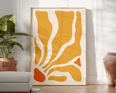 an orange and white art piece in a living room with potted plants on the floor