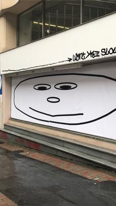 an advertisement on the side of a building with a face drawn on it's window