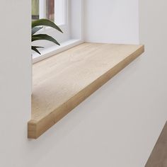 an empty room with white walls and wooden shelves, along with a plant in the window sill