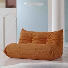 an orange bean bag chair sitting on top of a white floor next to a wall