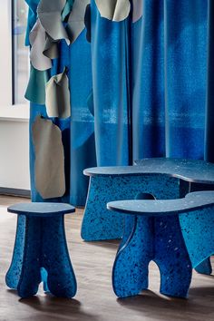 two blue benches sitting next to each other in front of curtains