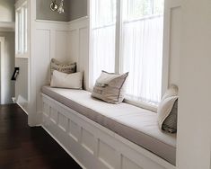 a white window seat with pillows on it