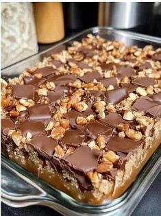 a close up of a cake in a pan on a table with chocolate and nuts