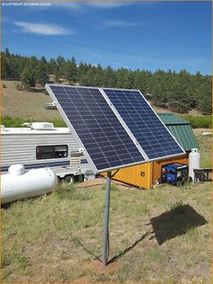 a solar panel sits on top of a pole in the middle of an open field