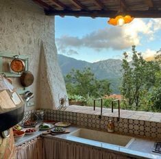 an outdoor kitchen with mountains in the backgroud and cooking utensils on the counter