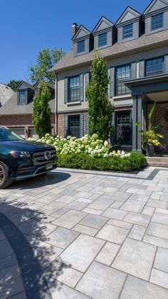 a blue truck parked in front of a large house with white flowers on the driveway