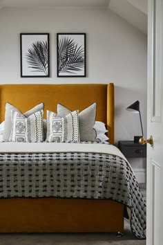 a bed with two framed pictures on the wall above it and pillows in front of it