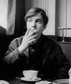 a black and white photo of a man sitting at a table with food in front of him