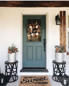 two planters with flowers are sitting on the front steps of a house, next to a blue door