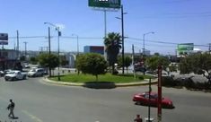 an intersection with cars and people walking on the sidewalk