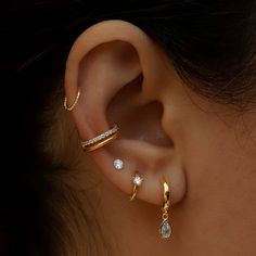 a woman wearing three different types of ear piercings