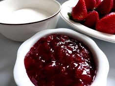 two bowls with strawberries and yogurt in them on a white table top