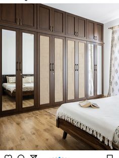 a bed sitting in a bedroom next to a large wooden cabinet with mirrors on it