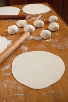 dough being made on a wooden table with rolling pin