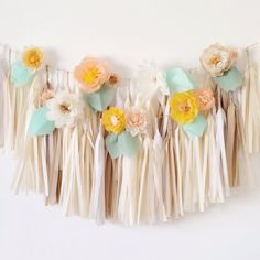 a garland with flowers and tassels hanging on a wall