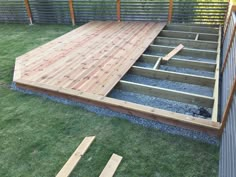 a wooden deck in the middle of some grass