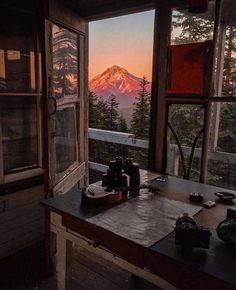 a table with some cups on it in front of a large window overlooking the mountains