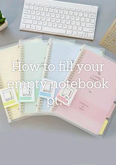 a pile of notebooks sitting on top of a desk next to a keyboard