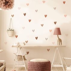 a room with hearts on the wall and a pink lamp next to a white table