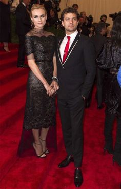 a man in a suit and tie standing next to a woman on a red carpet