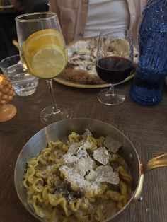 a bowl of pasta and some wine on a table