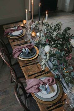 the table is set with plates and place settings, candles and flowers on top of them