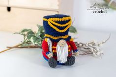 a crocheted nutcracker sitting on top of a table next to flowers