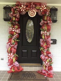 the front door is decorated for christmas with candy canes and bows on red ribbons