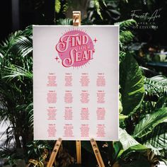 a sign that says find your seat in front of some plants and greenery at a wedding