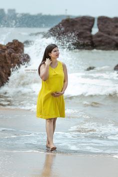 a pregnant woman walking on the beach talking on her cell phone