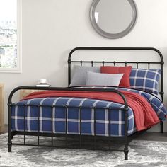 a black metal bed frame with red and blue plaid bedspread in a bedroom