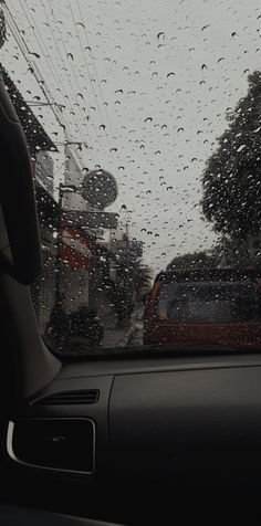 rain drops on the windshield of a car as it drives down a city street with traffic