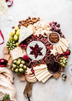 an assortment of cheeses, crackers, grapes and nuts arranged on a platter