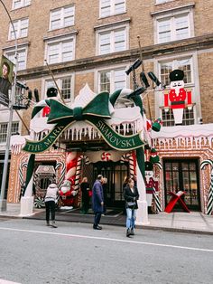 people are standing in front of a building decorated with christmas decorations and candy canes