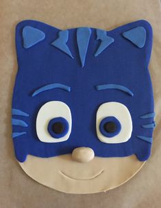 a cake shaped like a cat with blue eyes and ears on top of a piece of paper