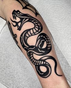 a man's arm with a black and white tattoo design on it, featuring a snake