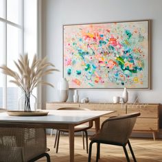 an abstract painting hangs above a dining room table