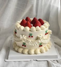 a three layer cake with strawberries on top and white icing, sitting on a plate