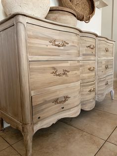 an old dresser with several drawers and a hat on it's top, in a room