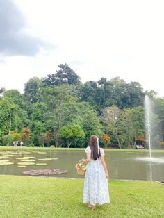 a woman standing in front of a pond holding a basket