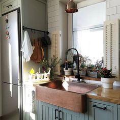 a kitchen sink sitting under a window next to a refrigerator