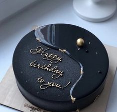 a black birthday cake with writing on it