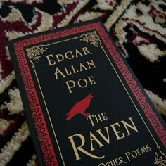 the raven by edgar allian poe is sitting on top of a red and black book