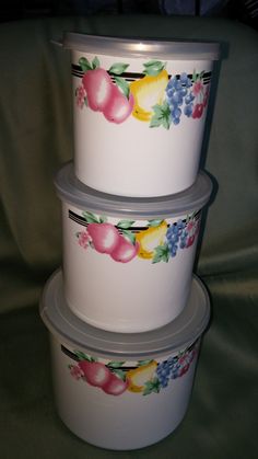 three plastic containers are stacked on top of each other with fruit painted on the lids