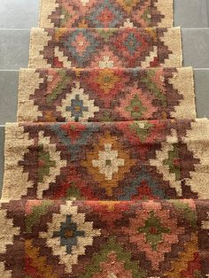 three rugs with different colors and designs on the carpeted steps in front of a tiled floor