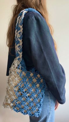 a woman is carrying a crocheted bag in blue and white yarn, back view