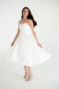 a woman wearing a white dress and high heels standing in front of a white background