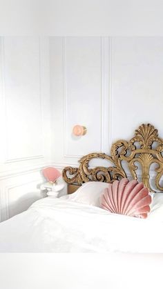 an ornate headboard with pink scallop pillows on it in a white bedroom