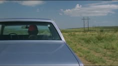 a car parked on the side of a dirt road next to a grass covered field