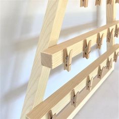 a wooden ladder with pegs hanging from it's sides on a white wall